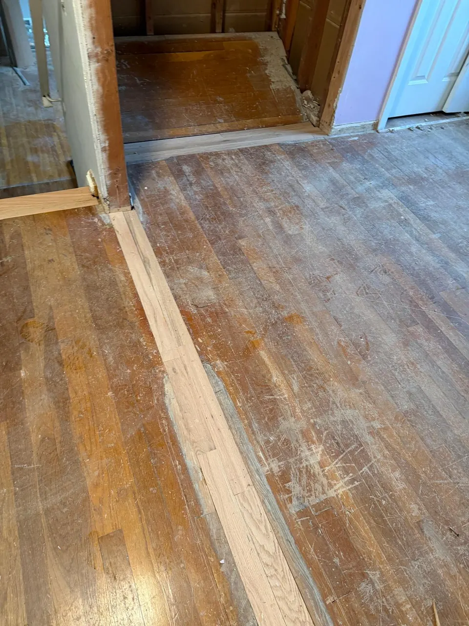Before: worn hardwood hallway with patched boards and a dull gray finish
