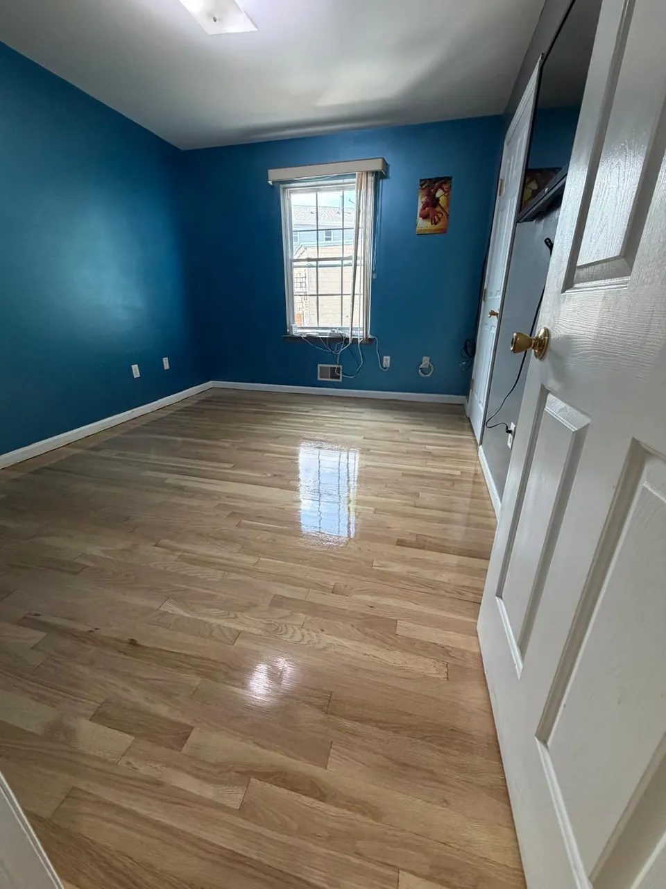 Bedroom with dark blue walls and a freshly finished light oak floor
