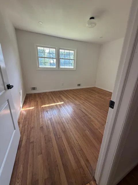 Small bedroom with a refinished red oak floor and a double window