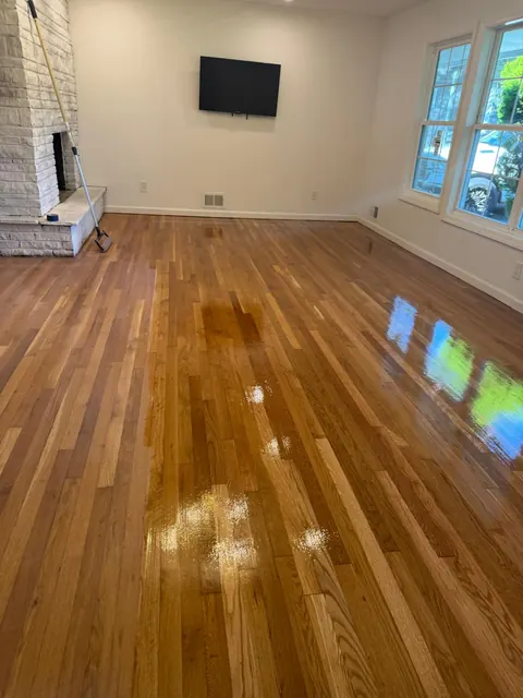 Open living room with stone fireplace and a glossy refinished oak floor