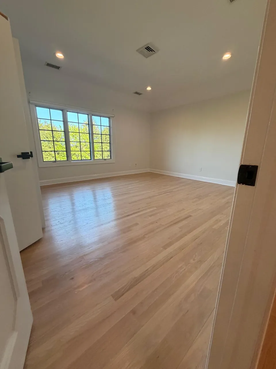 Bedroom with a new natural white oak floor and recessed lights
