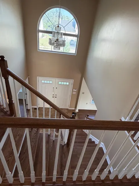 View down a foyer staircase with refinished oak handrail and white balusters