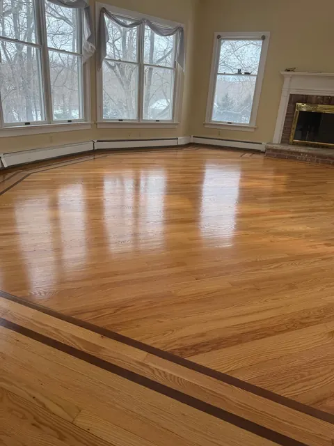 Living room with a bay window, fireplace and a dark inlay border in the oak floor
