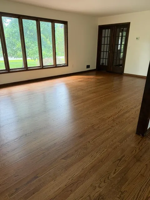 Living room with a wall of windows and a medium brown stained oak floor