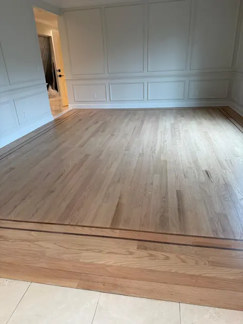 New white oak floor with a dark inlay border in a room with wainscoting