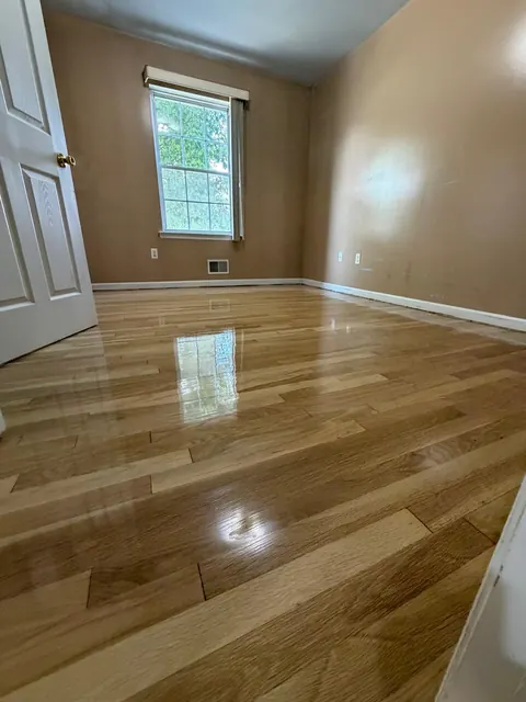 Bedroom with a refinished oak floor and tan walls, glossy finish