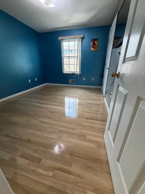 Bedroom with dark blue walls and a freshly finished light oak floor