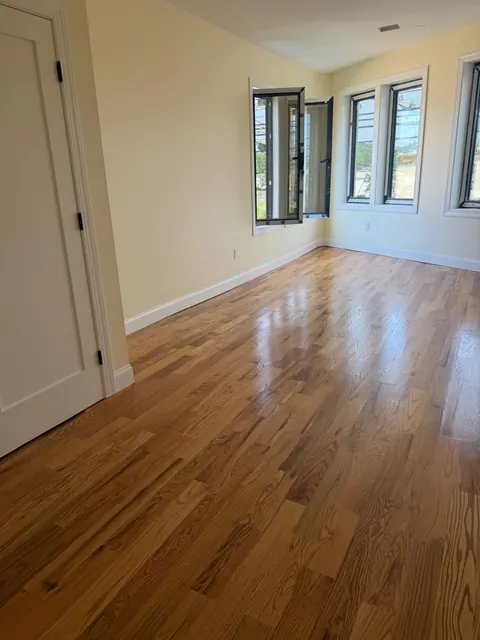 Corner bedroom with black window frames and a refinished oak floor