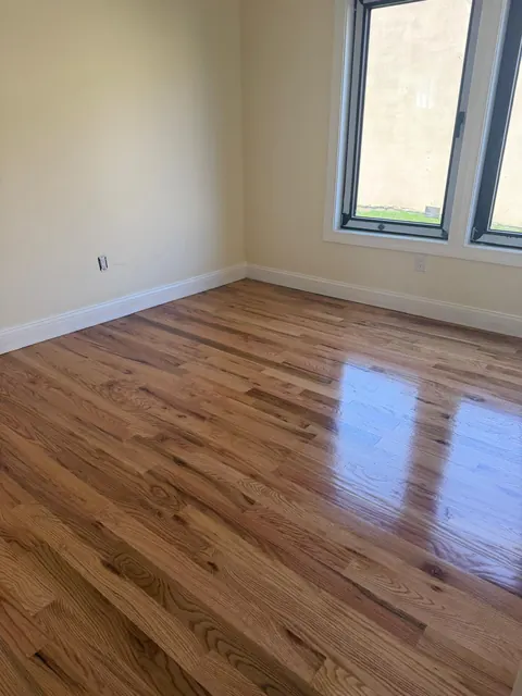 Bedroom with a refinished oak floor reflecting the window