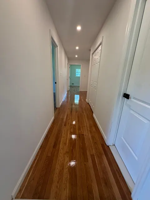 Long hallway with a refinished oak floor and white doors