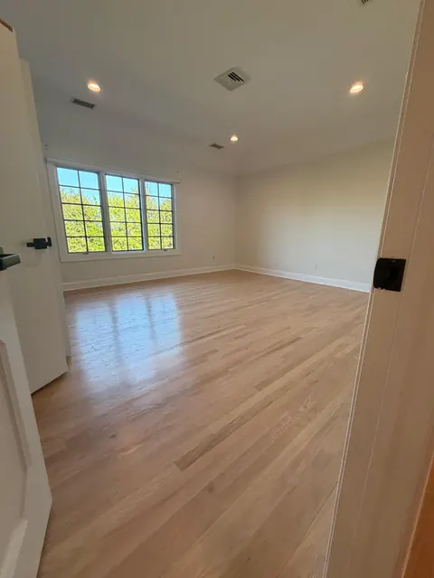 Bedroom with a new natural white oak floor and recessed lights