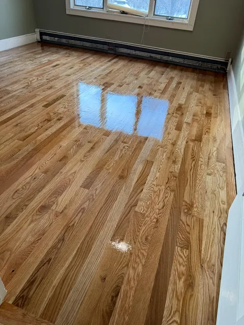 Refinished oak floor with a glossy finish beside a baseboard radiator