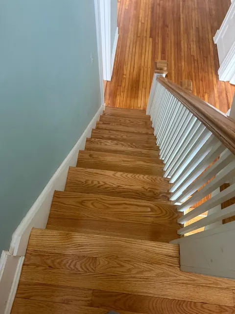 Staircase with natural oak treads and white risers, blue wall