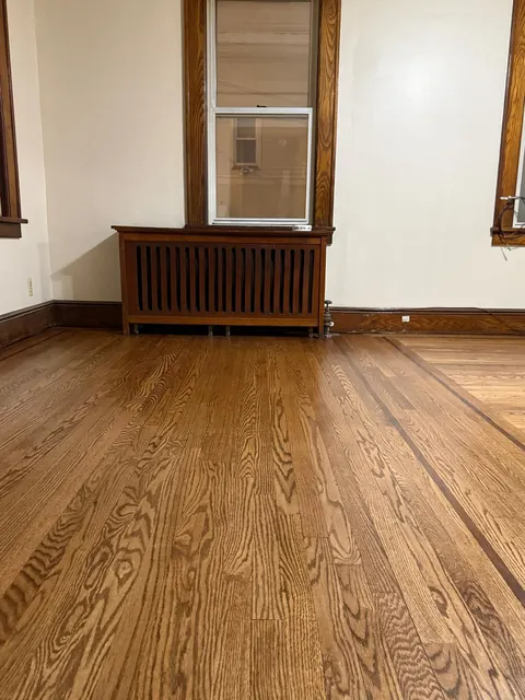 Older home with a radiator and a refinished red oak floor with a dark border